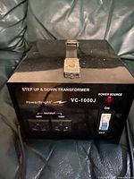 Front view of PowerBright VC-1000J step up and step down transformer showing latch, power switch, power indicator, and output voltage selection.