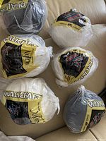 Six rolls of Qualicraft nylon knit or weave fabric in original packaging, showing colors black, white, and gray.