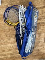 Photo showing badminton set components: multiple racquets, net, poles, and carrying bag.