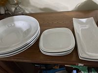 Overall view of the white bowls and plates set arranged on a wooden surface.