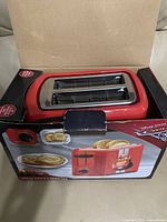 Top view of the red 2-slice toaster inside the box showing slots and part of packaging with Cars branding.