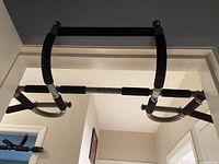 Doorway mounted chin up bar installed on door frame showing padded foam grips and metal construction.