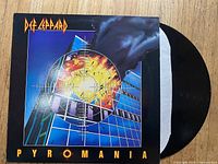 Photo shows Def Leppard Pyromania vinyl record and its album cover on a wooden surface.