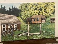 Front view of the oil painting showing wooden houses, fence, and landscape with trees in background.