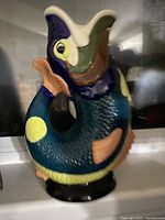 Front view of Gluggle Jug showing detailed fish design and colorful glaze.