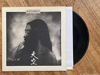 Vinyl record album cover with artistic black and white profile image, partially showing the record.