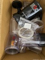 Box containing Magic Bullet blender cup, various blender parts, and bag of new replacement seals