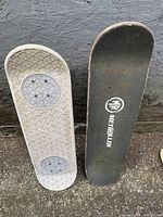 Photo of the bottom side of the two skateboards showing the designs and deck condition.