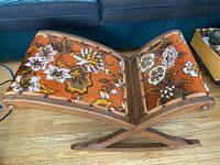 Side angled view showing wooden curved X rocker frame and floral upholstery.