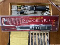 New Black & Decker pre-programmed digital grilling fork in sealed packaging alongside the box of vintage kitchen utensils.