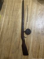 Full view of the wooden spear shooter including the wooden body and separate spear.