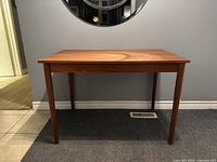 Front view of table showing overall design and condition against wall