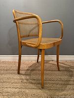 Front right three-quarter view of one armchair showing bentwood frame, cane seat and back