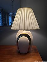 Front view of the vintage Art Deco style table lamp showing the ceramic base with cream and dark brown geometric design and pleated lampshade.