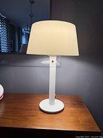 Full lamp view illuminated on wooden surface with visible shade and base.