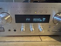 Front close-up view of the TEAC AG-H500 AM/FM stereo receiver showing the knobs and digital tuning display with FM 99.9 MHz frequency.