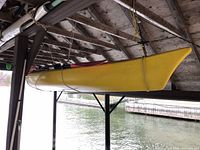 Side view of yellow kayak suspended under boathouse, showing hull shape and cockpit outline