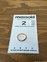Ring placed on MaxSold notes and measurements card, top-down view