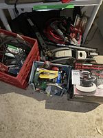 Overview photo showing crates and the stacked tools including the buffer/polisher box, jumper cables, car jack, and other tools on the floor.