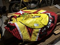 Folded Airhead towable water tube in bright red, yellow, black, and white colors with attached yellow tow rope and green float valve handle.