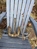 Photo showing the full anchor with attached chain on a blue wooden chair outdoors, highlighting overall condition and size