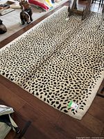 Full view of rectangular cheetah print area rug on floor showing pattern and condition.