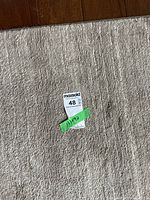 Close-up of the beige surface of the rug with a small tag showing size 133x92.