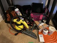 Overall assortment of tools and accessories including yellow steam cleaner, tool bags, wooden blocks and soldering materials