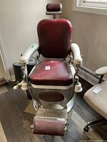 Front view of burgundy vinyl barbershop chair on round pedestal base