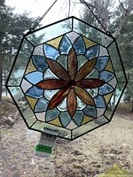 Full view of the stained glass panel hanging, showing the floral pattern and octagonal shape.