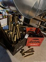 View of brass pipes and handles in two crates and some handles laid out on the floor.