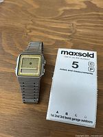 Watch laid flat on wood surface next to MaxSold notes card