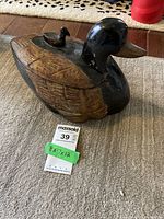 Closed view of the wooden duck box showing carved and painted details with a small duck figure on the lid.