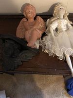 Porcelain ballerina doll and clay cherub figurine displayed on a wooden surface