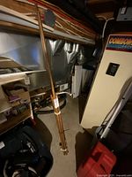 Copper pipes bundled together leaning against a furnace in a basement or utility area.