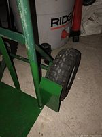 Close-up of the hand truck wheel and base plate showing the pneumatic tire tread and metal construction.