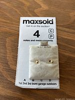 Front view of 14K gold stud earrings on a display card stamped '14 KT. GOLD' with one earring missing the post tip.