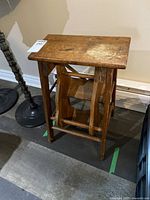 Wooden folding step ladder seen folded and standing upright, showing its general condition and structure.