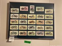 Overall view of the complete framed collection of 25 motorcycle cards arranged in five rows within a black frame on dark blue matting.