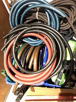 View of coiled garden hoses and braided ropes piled in a box.