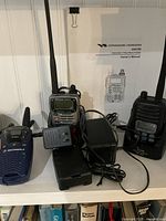 Standard Horizon HX470S submersible marine radio with antenna, charger, battery, and owner's manual on white shelf.