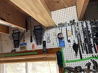 Pegboard view of combination wrenches and some socket wrenches organized on hooks, showing comprehensive tool set arrangement.