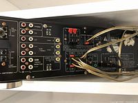 Rear panel showing multiple audio and video RCA input and output connectors, AM/FM antenna connections, and speaker wire terminals with wires attached.