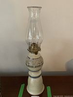 Full view of the pottery oil lamp including the glass chimney and base with tree etching.