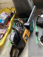 Overall side view of Poulan chainsaw with protective chain bar cover, showing condition and included box of accessories behind it