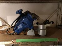 Side view of blue electric chain saw sharpener with grinding wheel and adjustable guide mounted.