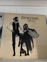 Fleetwood Mac 'Rumours' album cover with man and woman in vintage attire.