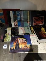 Photo showing a variety of vinyl record albums stacked and spread on a table, highlighting several album covers including Victory at Sea.