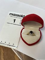 Ring presented in red heart-shaped case next to MaxSold card