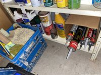 Shelf with adhesive tubes, cleaning supplies, brushes in crates and jars
